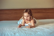 © serperm73 - Charming attractive baby girl 4-5 years old on bed with smartphone or cell phone in hand.