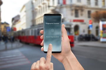 Poster - Fingerprint scanner security app on moder mobile phone. Man holding and touch round phone screen. Street in background.