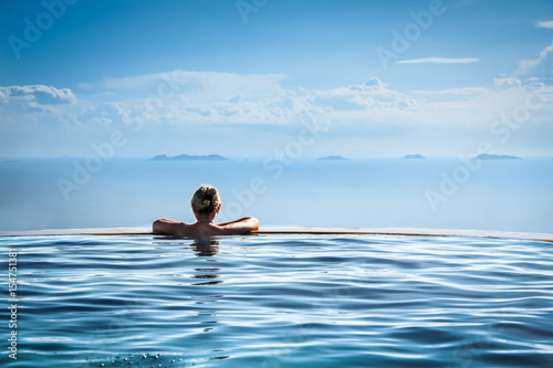 Plakat Kobieta relaksuje w nieskończoności pływackim basenie patrzeje widok