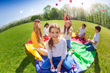 Wall Mural - Girl sitting on green lawn holding colorful balls