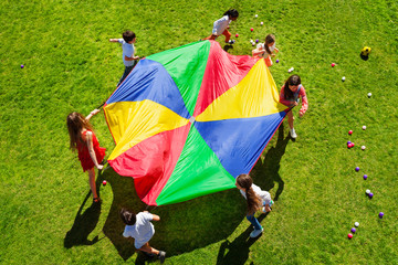 Kids going round in a circle with bright parachute