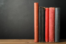 Row Of Books With Blank Spines On Desk With Chalkboard Background