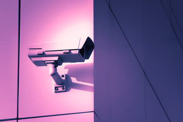 Monitoring security camera on building background. toned violet