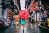 People woman walking in chinatown shopping street. Rainy day girl tourist under red oriental umbrella in narrow alleys on china travel in Shanghai.
