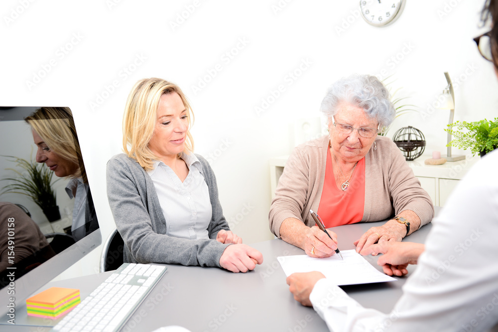elderly senior woman with daughter signature legacy heritage testament document in a lawyer notary office - obrazy, fototapety, plakaty 