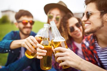 Group of friends enjoying party.people are drinking beer and laughing
.The guy plays the guitar. Everyone has a great mood. Summer time. 
