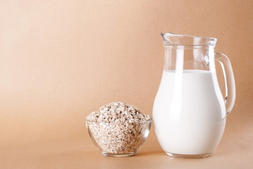 Poster - Raw oatmeal in a bowl and milk in a jar on a beige background