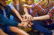 © maxbelchenko - young people putting their hands together. Friends with stack of hands showing unity and teamwork.Group of friends enjoying party. Everyone has a great mood. Summer time.