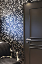 Resting Corner With Gray Door With Black Wallpaper And Golden Flowers And Gray Armchair