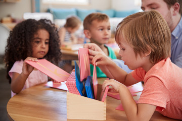 Teacher And Pupils Working With Letters In Montessori School