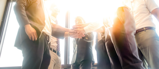 Wall Mural - Business people join hand together during their meeting with sun rays aura background.