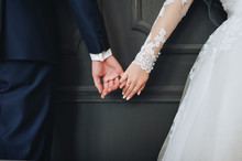 Newlyweds Hold Hands. Grey Background.