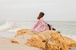 © COLOR PHOTO - Young woman is covered with a rug sits on the seashore and reads an ebook.