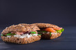 Rye sandwich with fish salmon with tomatoes and cream cheese. Wooden black background