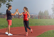 © Nastassia Yakushevic - Young adult woman giving high five to partner after a run.