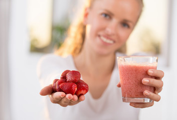 Girl holding strawberry and smoothie