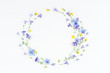 Wreath made of bell flowers, pansy flowers and yellow flowers on white background. Flat lay, top view