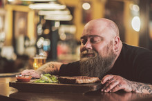 Man Savoring Grilled Meat In Pub