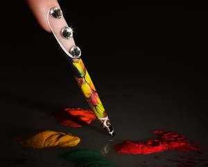 Wall Mural - The girl's finger. Female manicure. Acrylic Powder. Long colored acrylic nails on a dark background.