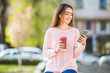 © F8  \ Suport Ukraine - young woman with coffee cup using smartphone walking in city, outdoors