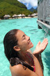 Woman enjoying water from outdoor shower showering in private overwater bungalow hotel in Tahiti, luxury spa resort travel vacation. Asian girl showering after swim in the ocean water.