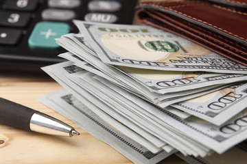 Money (dollars), purse, pen and calculator on a wooden table. Close-up