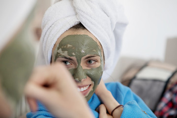 Wall Mural - Mom and her daughter chilling in the bedroom and making clay facial mask.