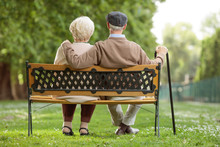 Senior Couple Sitting On A Wooden Bench In The Park
