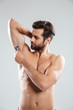 © Drobot Dean - Portrait of a young bearded man shaving his armpit