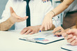 © cameravit - Group of business people looking at the clipboard with graphics.