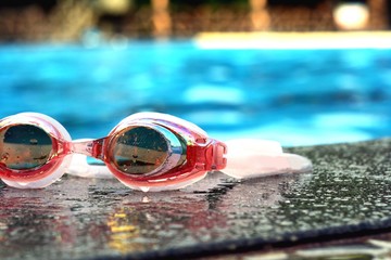 Pair of swimming goggles beside a swimming pool