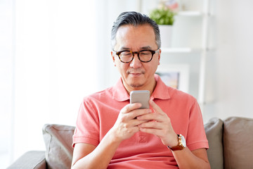 man with smartphone sitting on sofa at home