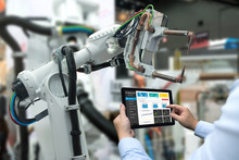 Engineer Hand Using Tablet, Heavy Automation Robot Arm Machine In Smart Factory Industrial With Tablet Real Time Monitoring System Application. Industry 4th Iot Concept.