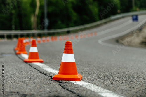 Fotografía bright orange traffic cones on dark asphalt serpentine mountain roads