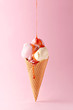Ice cream cone with strawberry topping on a pink background. Copy space