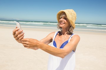 Wall Mural - Happy woman using smart  phone while standing at beach