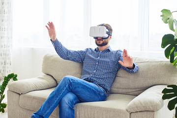 Wall Mural - Stylish male with beard working in VR glasses sitting on sofa