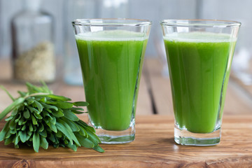 Two green barley grass shots on a wooden background