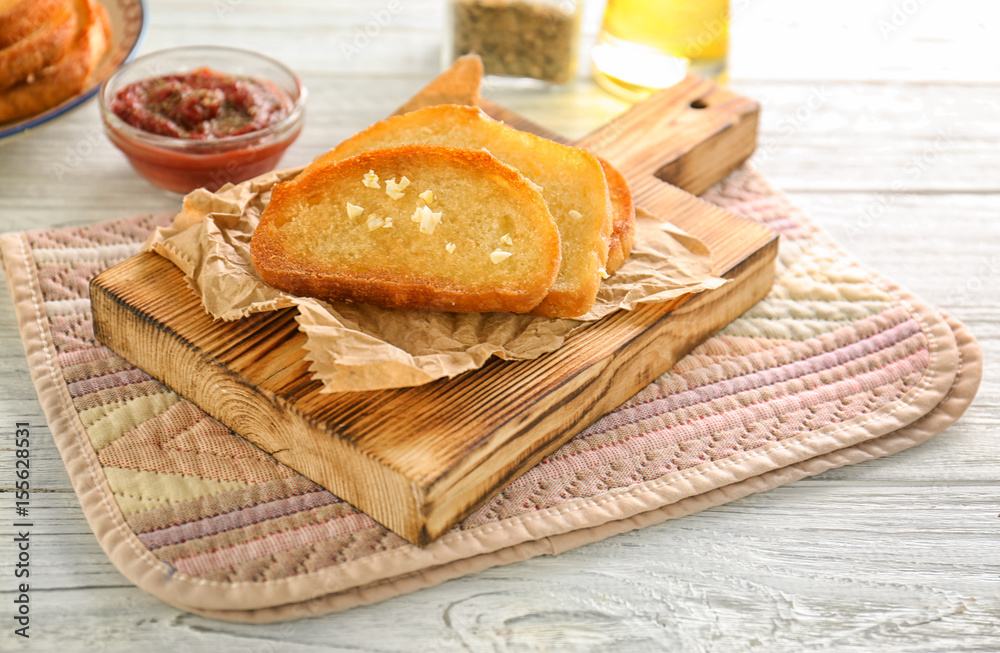 Tasty garlic French bread slices on wooden table