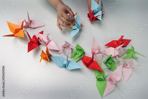 A Helper Lays Paper Cranes On A Table During A Origami