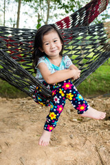 Wall Mural - Cheerful child enjoying and relaxing in hammock, outdoor on summer day.