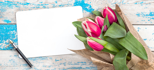 Wall Mural - Bouquet tulips with empty sheet and pen on the old wooden background. Greeting card for women's day.