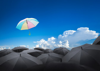 Wall Mural - abstract umbrella flying over many black umbrellas with beautiful sky, leadership background concept.