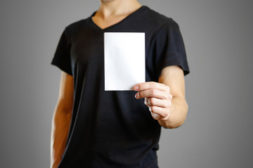 Wall Mural - Man in a black shirt holding a white sheet of paper. Empty flyer. Isolated