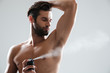 Horizntal image of young man using deodorant