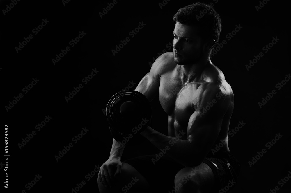 Monochrome low key light shot of a shirtless athletic man working out ...