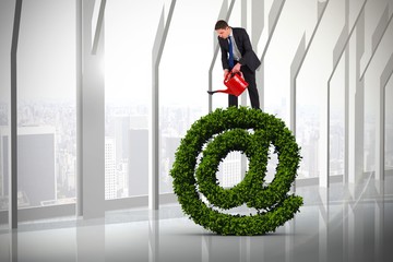 Poster - Composite image of businessman holding red watering can