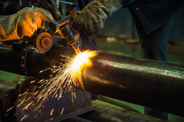 Acetylene torch cutting tube industrial for construction fabrication with bright sparks in steel factory.