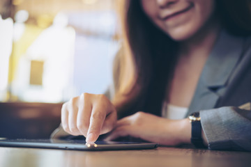 A business woman's hand pointing , touching and using tablet with blur background in cafe