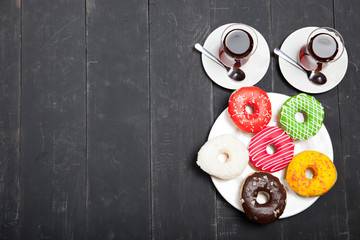 Wall Mural - Cups of tea and donuts on a black wooden background